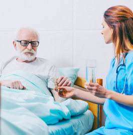 caregiver giving medication to old man